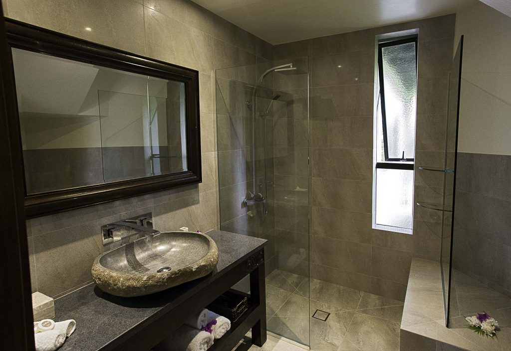 Premium Lagoon View Villa featuring an oval-shaped stone-built bathroom basin overlooking a glass-see-through shower room with water resistant glossy tiles