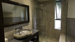 Premium Lagoon View Villa featuring an oval-shaped stone-built bathroom basin overlooking a glass-see-through shower room with water resistant glossy tiles